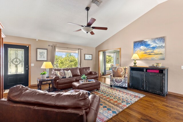 living room featuring a ceiling fan, visible vents, wood finished floors, baseboards, and lofted ceiling