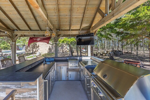 view of patio with exterior kitchen and a grill