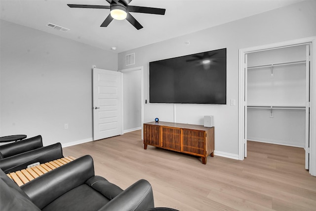 living area featuring visible vents, a ceiling fan, baseboards, and wood finished floors