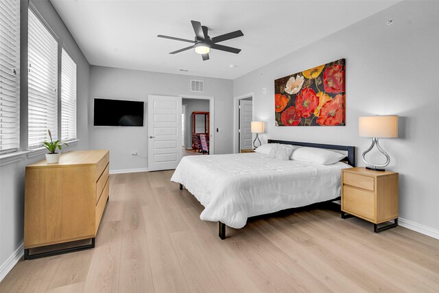 bedroom with baseboards, light wood finished floors, ceiling fan, and visible vents