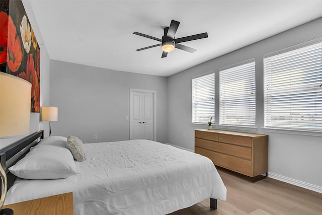 bedroom with baseboards, ceiling fan, and light wood-type flooring