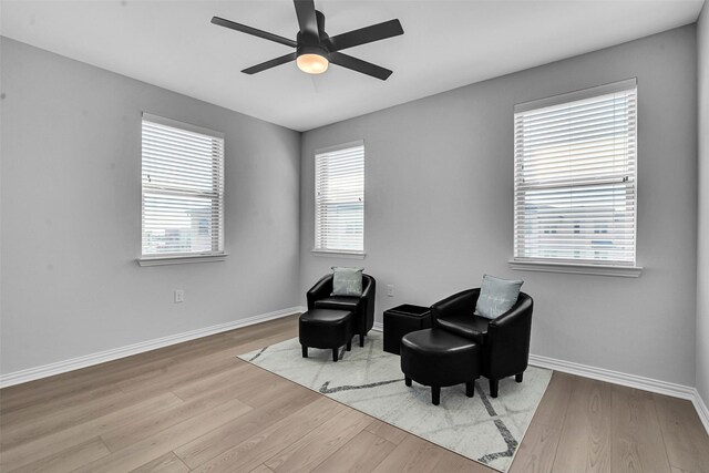sitting room with baseboards, ceiling fan, and wood finished floors