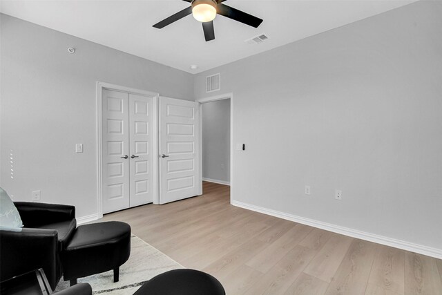 sitting room with visible vents, a ceiling fan, light wood-style floors, and baseboards