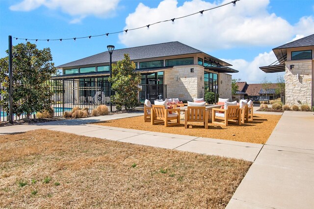 view of front facade with fence, a swimming pool, an outdoor living space, and stone siding