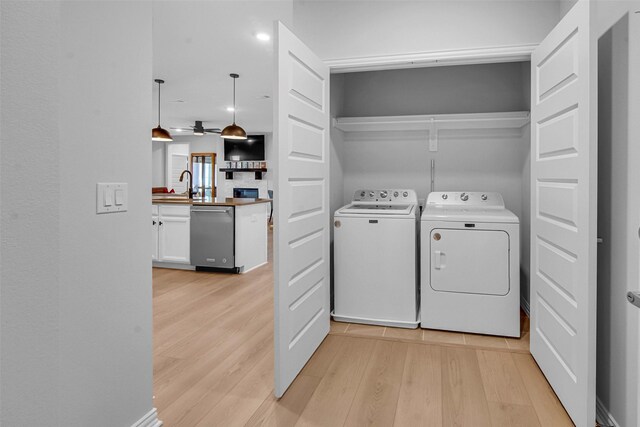 laundry area featuring laundry area, a ceiling fan, a sink, light wood-style floors, and washer and clothes dryer