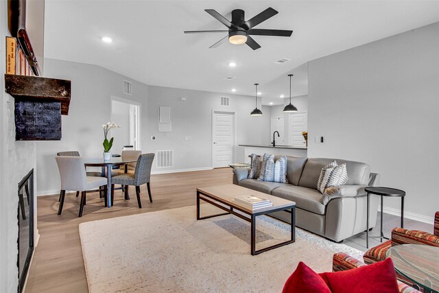 living room featuring visible vents, a ceiling fan, baseboards, and light wood-style flooring