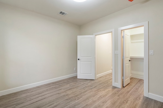 518 S Cockrell Hill Rd, Cockrell Hill, TX 75211 - unfurnished bedroom with visible vents, light wood-type flooring, baseboards, a closet, and a spacious closet