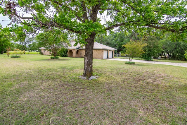 view of front of property with an attached garage, driveway, metal roof, and a front yard