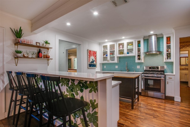 1635 Taft St, Dallas, TX 75208 - kitchen featuring stainless steel range with gas stovetop, white cabinets, crown molding, visible vents, and wall chimney range hood