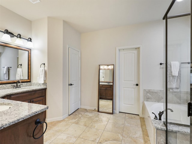 full bath featuring baseboards, two vanities, a sink, and a garden tub