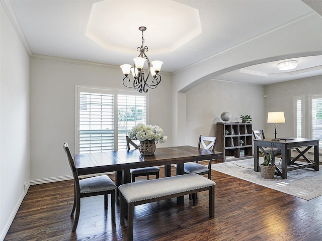 dining space featuring arched walkways, an inviting chandelier, dark wood-style floors, and a raised ceiling