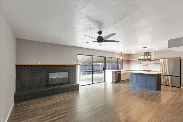 unfurnished living room with a textured ceiling, ceiling fan, and wood finished floors