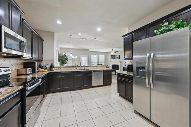 kitchen featuring appliances with stainless steel finishes, light stone countertops, a sink, a peninsula, and recessed lighting