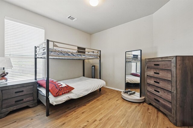 bedroom featuring visible vents, light wood-style floors, baseboards, and multiple windows