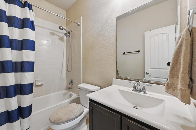 full bathroom featuring vanity, a textured wall, shower / bath combination with curtain, and toilet
