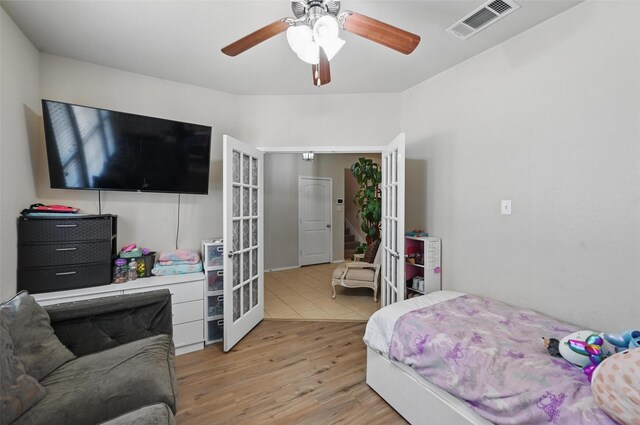 bedroom featuring ceiling fan, visible vents, french doors, and light wood-style floors