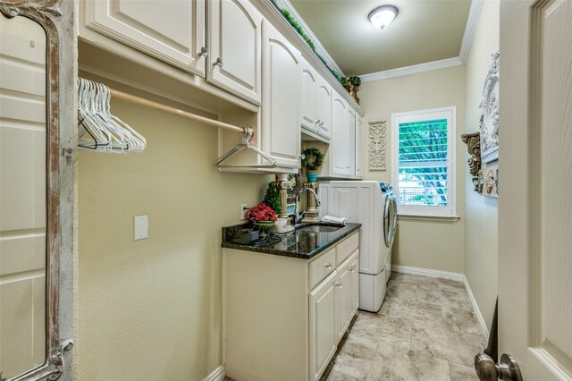 clothes washing area with crown molding, washing machine and dryer, cabinet space, a sink, and baseboards