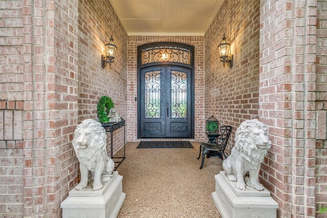 property entrance featuring french doors, a porch, and brick siding