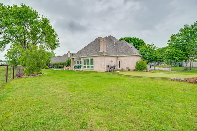 back of house featuring a lawn, a fenced backyard, a chimney, and a shingled roof