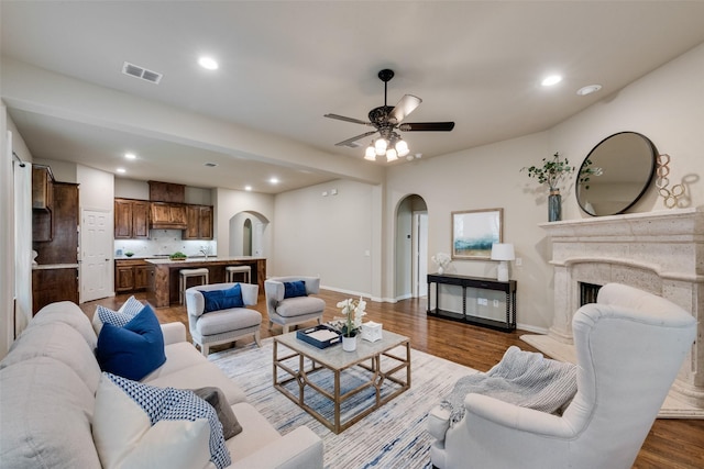 living room featuring arched walkways, baseboards, wood finished floors, and visible vents