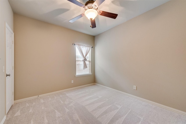 empty room with light colored carpet, a ceiling fan, and baseboards