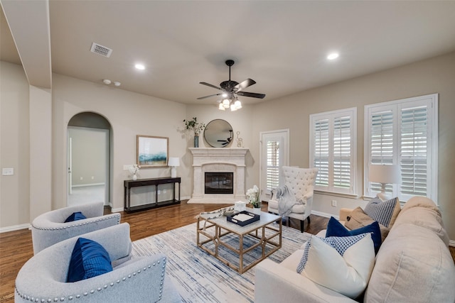 living room featuring visible vents, baseboards, ceiling fan, and wood finished floors