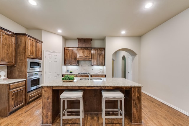 kitchen with backsplash, appliances with stainless steel finishes, a sink, and a kitchen bar