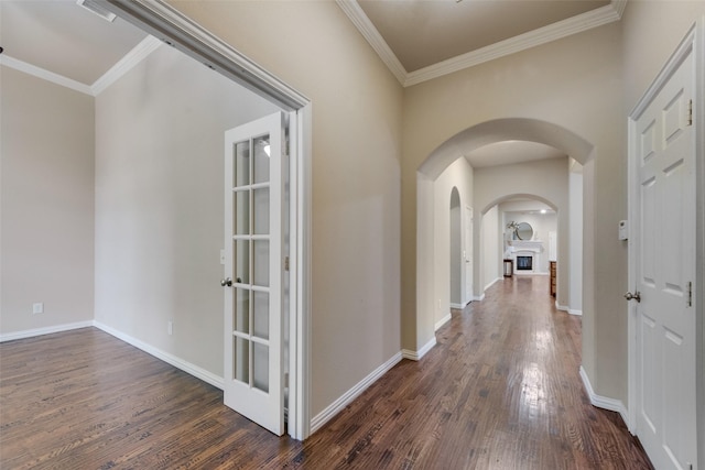 hall featuring baseboards, ornamental molding, arched walkways, and dark wood-style floors