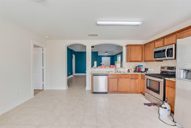 850 Levi Ln, Forney, TX 75126 - kitchen with visible vents, a sink, arched walkways, light tile patterned floors, and stainless steel appliances
