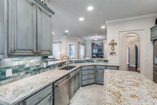 kitchen featuring a sink, dishwasher, arched walkways, gray cabinetry, and ornamental molding