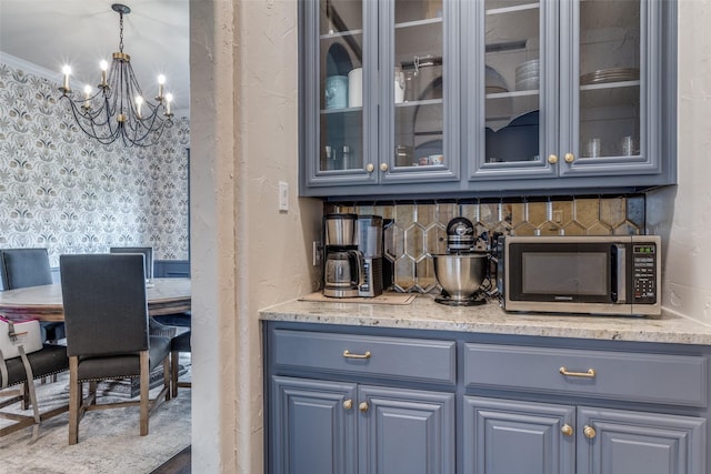 bar with stainless steel microwave, backsplash, a chandelier, and decorative light fixtures