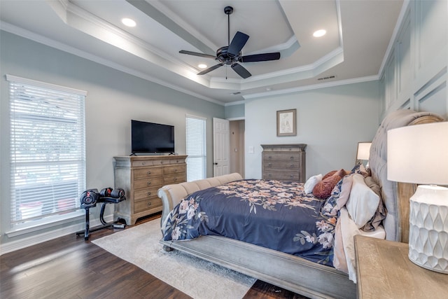 bedroom with visible vents, ornamental molding, wood finished floors, baseboards, and a raised ceiling