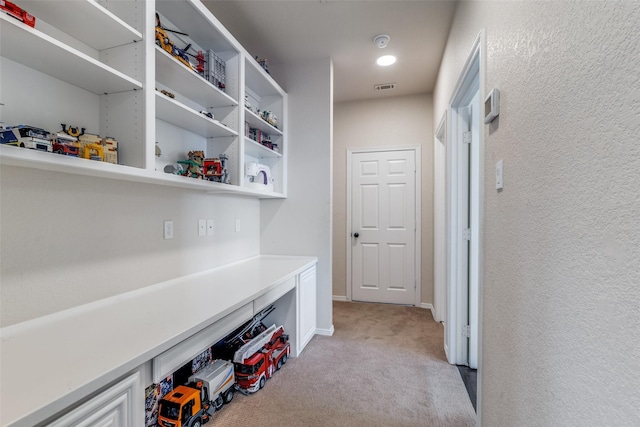 mudroom with baseboards, visible vents, and light carpet