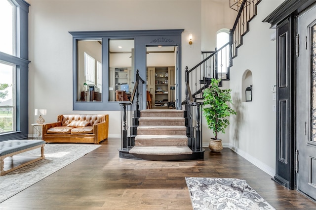 foyer entrance with baseboards, dark wood-type flooring, stairway, and a towering ceiling