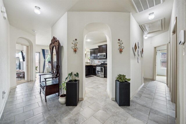 corridor featuring visible vents, attic access, arched walkways, and a wealth of natural light
