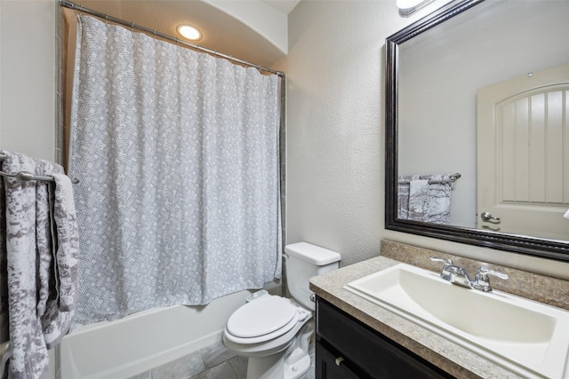 bathroom featuring vanity, a textured wall, shower / bath combo with shower curtain, and toilet