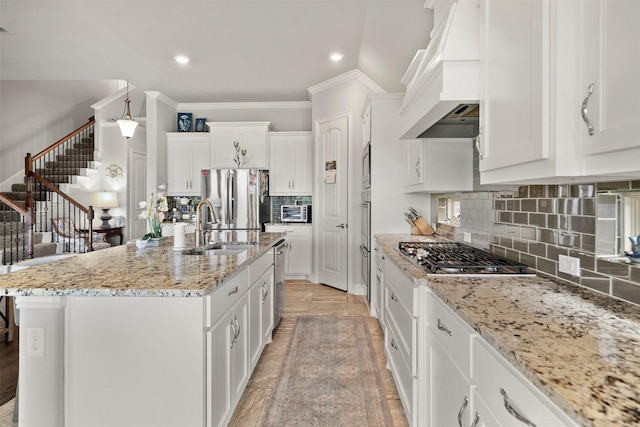 kitchen featuring a sink, white cabinetry, premium range hood, and stainless steel appliances