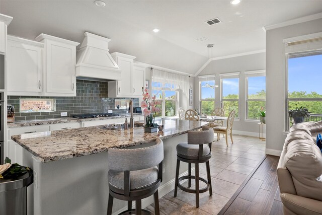 kitchen with a sink, stainless steel gas cooktop, backsplash, visible vents, and custom exhaust hood