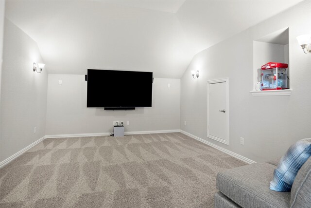 home theater room featuring baseboards, lofted ceiling, and light carpet