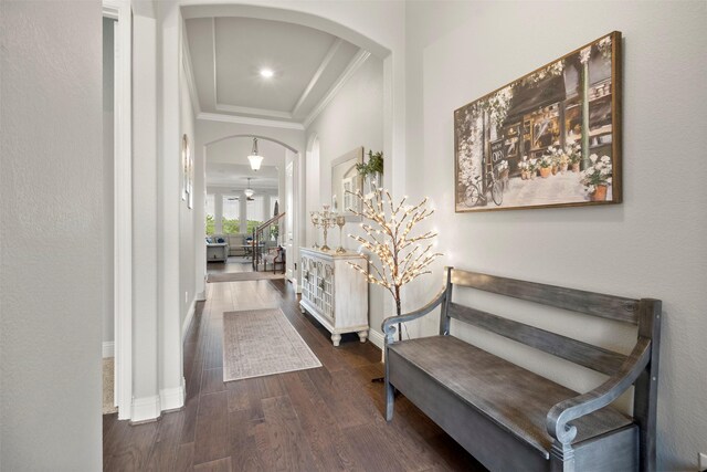 foyer with crown molding, arched walkways, baseboards, and wood finished floors