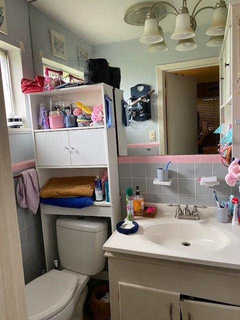 bathroom featuring vanity, toilet, and tile walls