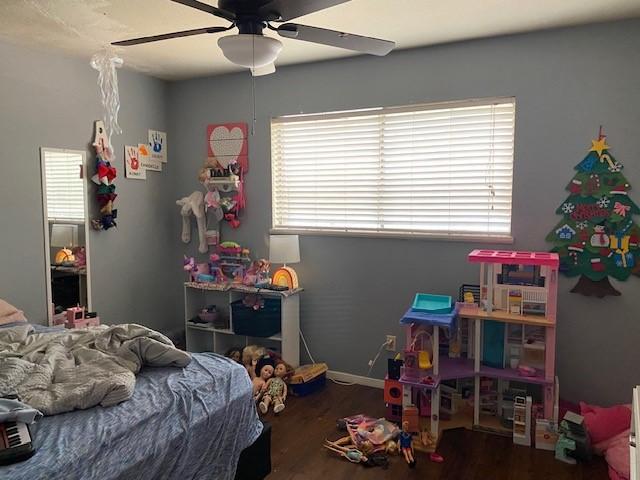 bedroom with a ceiling fan, wood finished floors, and multiple windows