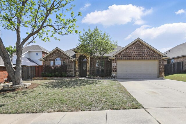 view of front of home with brick siding, fence, a front lawn, and a garage