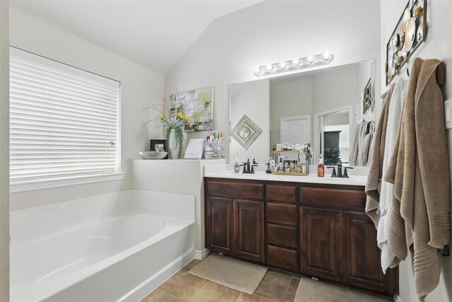 full bath featuring a sink, tile patterned flooring, double vanity, lofted ceiling, and a garden tub