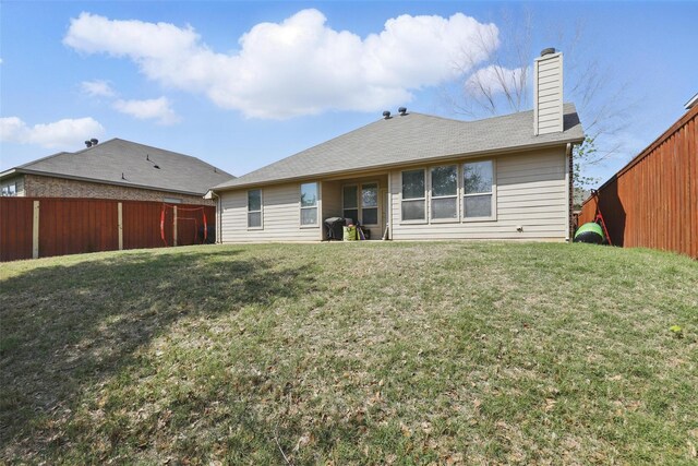 back of house featuring fence, a yard, and a chimney