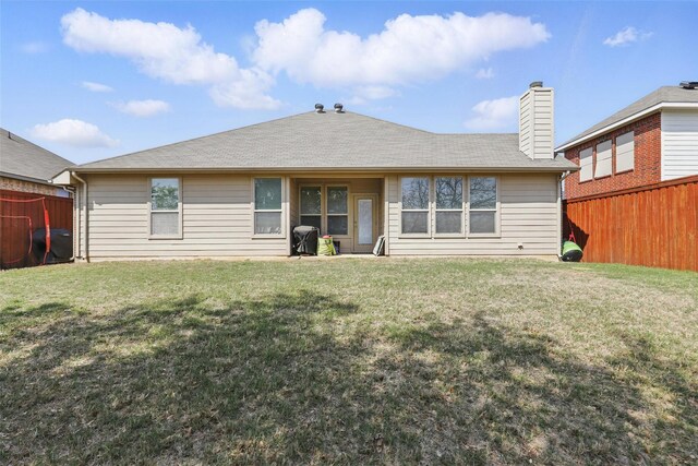 rear view of property with a yard, fence, and a chimney