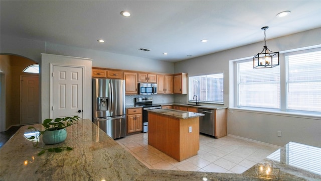 kitchen with light tile patterned floors, appliances with stainless steel finishes, a center island, and arched walkways