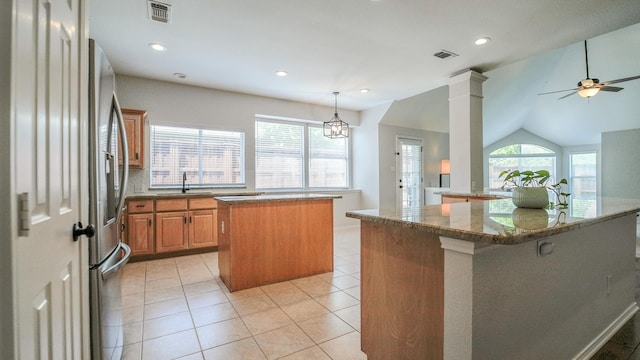 kitchen with a ceiling fan, visible vents, a sink, and a center island