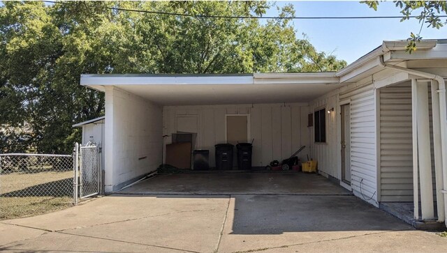 view of car parking with fence, driveway, and a carport