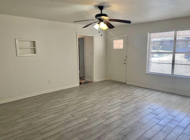 interior space with baseboards, a ceiling fan, a textured ceiling, and wood finished floors